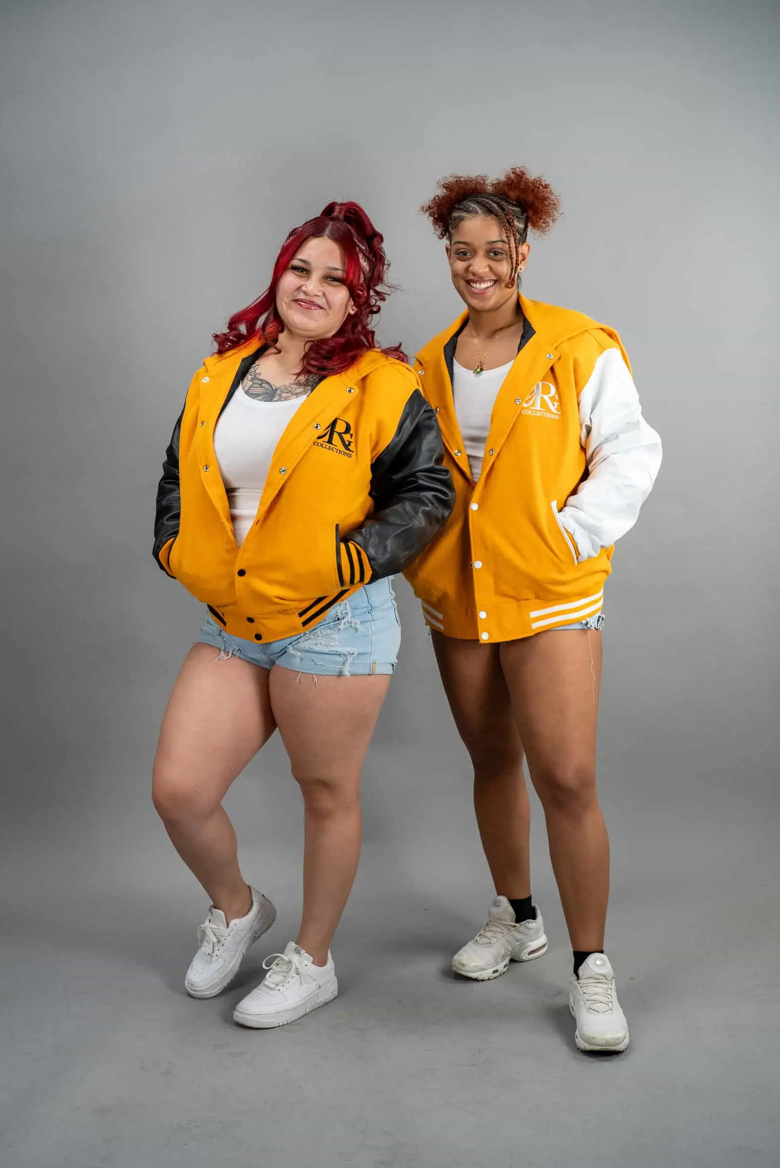 Two women wearing Reign Gear yellow and white water-repellent hooded varsity jackets.